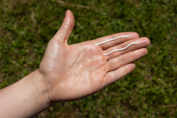A man applying the correct amount of sunscreen for face and neck (two finger lengths).