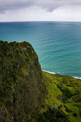Narrow promontory rising high above over calm blue waters of Tasman Sea. Te Toto Gorge Lookout, Raglan, New Zealand