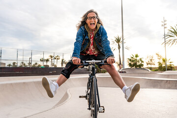 Beautiful confident senior woman with grey hair skateboarding outdoors