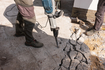 Construction work. Construction worker chisels the concrete slab with a hammer drill