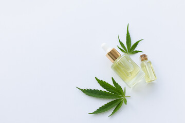 Two small bottles with cannabis oil and fresh cannabis leaves. Top view, copy space.