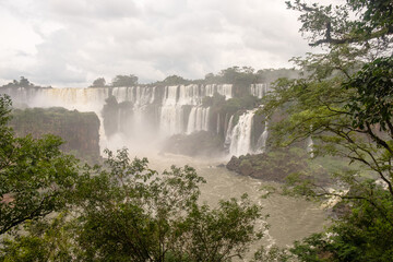 Scenic panorama of the Iguazu Falls behind the foliage of the forest, Argentina