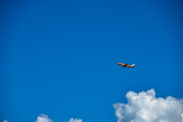 青空を滑空するオレンジ旅客機