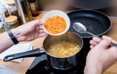 Chef at the kitchen preparing lentils soup with cauliflower and broccoli