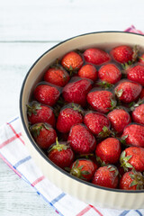 Strawberries in a bowl with fresh water on wooden table. Close-up. Washing and cleaning organic sweet berries before eating.