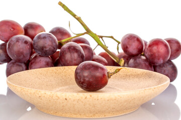 One sweet grape berry on a ceramic saucer, macro, isolated on white background.