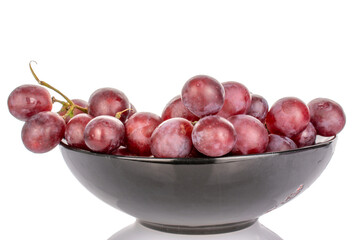 One bunch of sweet grapes in a black ceramic plate, macro, isolated on white background.