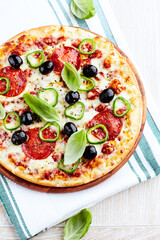Pizza with salami, jalapeno pepper and black olives. Home made food. Concept for a tasty and hearty meal. Close up.