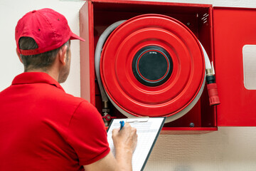 Technician performing inspection of fire hose cabinet. Fire protection systems maintenance for...