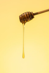 Golden honey dripping from a wooden dipper. 