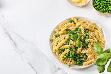 Vegetarian pasta with boiled green peas and basil on plate