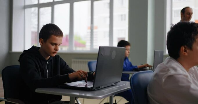 Smart Boys Students In Classroom, Pupils Working With Laptops Ad Teacher Walking In Room