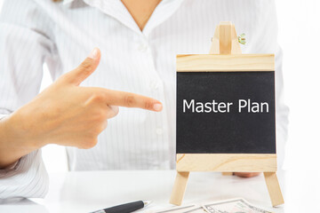 A woman pointing at a blackboard with the word Master plan written on it
