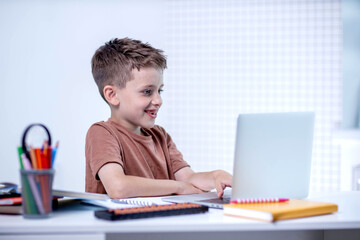 School kid with computer having video conference chat with teacher and class group. Child studying from home. Homeschooling. Modern gadgets for education. Screen time control. Online remote learning.