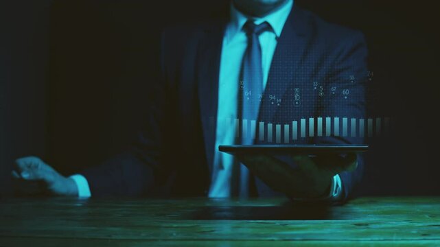 A businessman in a suit holds a graphics tablet above which there is a hologram of a Chinese candlestick chart above which a linear graph moves between key points with digital indicators. Cg