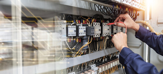 Electricity and electrical maintenance service, Engineer hand holding AC voltmeter checking electric current voltage at circuit breaker terminal and cable .	