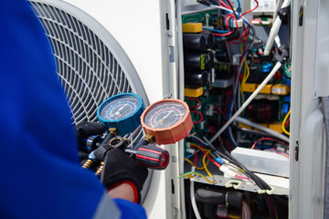 Air conditioner service .The air conditioner technician is using a gauge to measure the refrigerant...