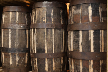 Vintage wooden barrels with alcohol stand on shelves, close-up.