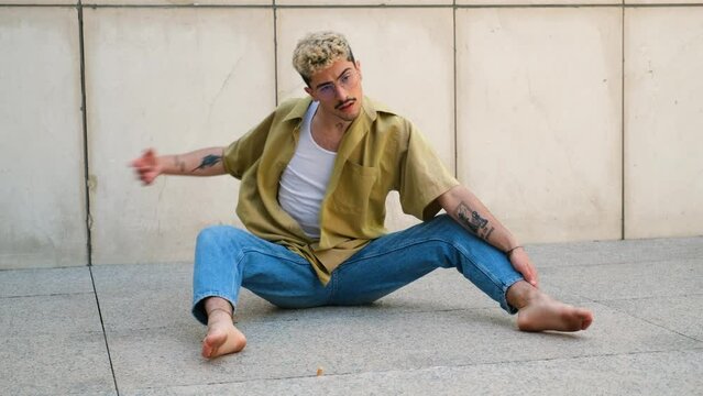 Young man barefoot, with dyed hair is dancing contemporary dance