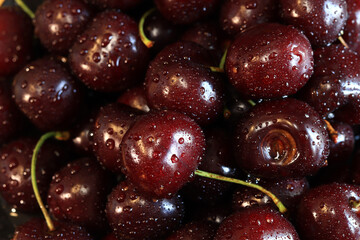 Cherry berries close-up. Wet sweet ripe cherries. Background. Dark red cherries with green stems covered with fine splashes of water. Summer berries, vitamins. Close-up of red berries