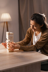 Happy woman playing a wooden block game at table, moving a wooden block. game and leisure