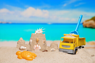 Sand castle and child toys on sand beach at tropical resort. Family vacation. Relax on the beautiful sea coast beach. Azure water on the ocean, sea coast resort. Summer holidays. Blue sky. Copy space.