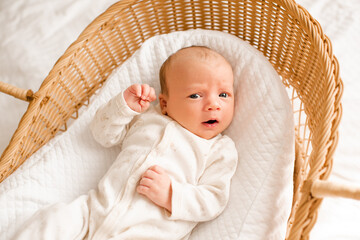 Cute baby wake up in baby straw bassinet close up. Good morning. Childhood. Top view.