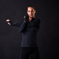 Woman, portrait and stretching arms in studio for fitness, health or self care on black background. Female athlete, face and warm up for crossfit, wellness and performance goals at sports competition