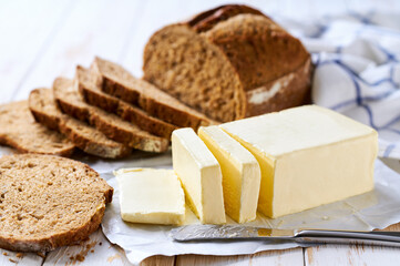 Sliced rye bread with butter on a white wooden table, selective focus.