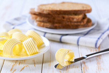 breakfast with butter and multigrain bread , in the background you can see a plate with a few slices of rye bread.