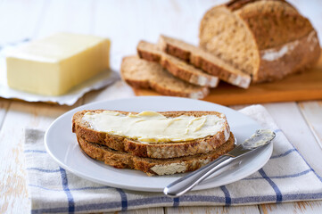 Fresh crusty buttered rye bread slices with butter  on a wooden table