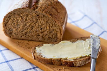 Healthy wholemeal bread with butter on a wooden table.