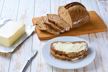 Flat lay composition with tasty rye bread and butter on wooden table.