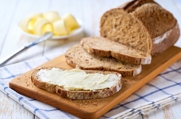 slice home baked rye sourdough bread with butter on a wooden table.