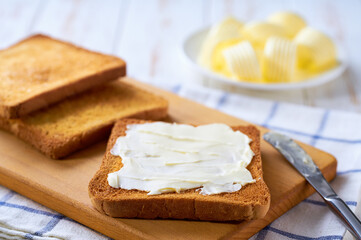 spread butter on a golden crispy pieces of toast on a cutting board, selective focus.