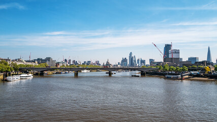 Obraz premium Looking along the river Thames to Waterloo Bridge, with St Pauls Cathedral and the City of London beyond. Panoramic view in summer.