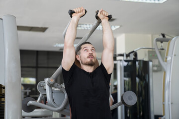 Male athlete using exercise machine during strength training in gym. Man workout using exercise...