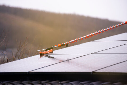 Cleaning a photovoltaic system with a telescopic washing brush and water