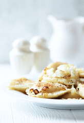 Dumplings with potato and cottage cheese stuffing (pierogi). Traditional Polish Christmas Dinner. Bright background.