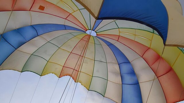 A colorful parachute flying through a cloudy sky 