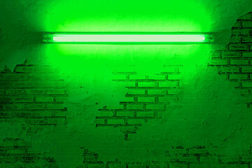 Fototapeta premium green neon light bulb on brick wall. Background texture of empty old brick wall with glowing green neon lamps. 