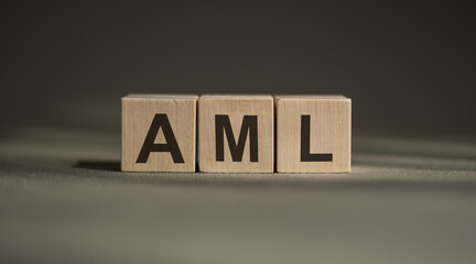 wooden cubes with the word AML stand on a financial background, business concept. AML - short for ANTI-MONEY LAUNDERING