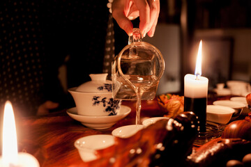 candles on the table,girl's hand pours tea from a glass teapot
