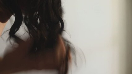 Woman applies a balm or condition styling to wet hair using the praying hands technique