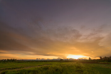 Golden Evening Light: Peaceful Meadow, Mountains, and Orange Sky - Ideal for Background Design