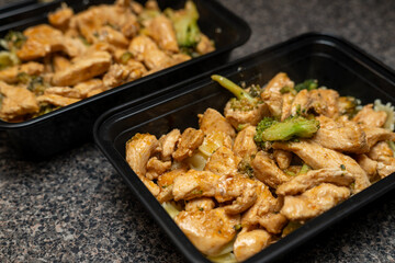 Meal Prep chicken and broccoli in a black meal prep container. Lunch for work, healthy food.
