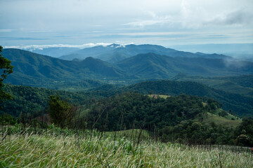 Lush green mountains with a cloudy summer sky stretch into the distance