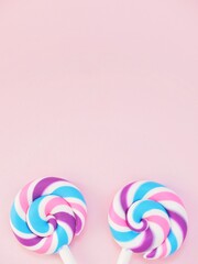 Two colorful lollipops against a pink background. Vibrant candy pops and space to add personalized text