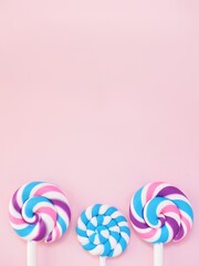 Three colorful lollipops against a pink background. Vibrant candy pops and space to add personalized text