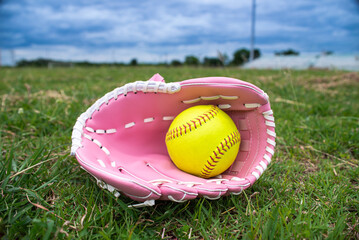 Green softball in pink softball glove on field